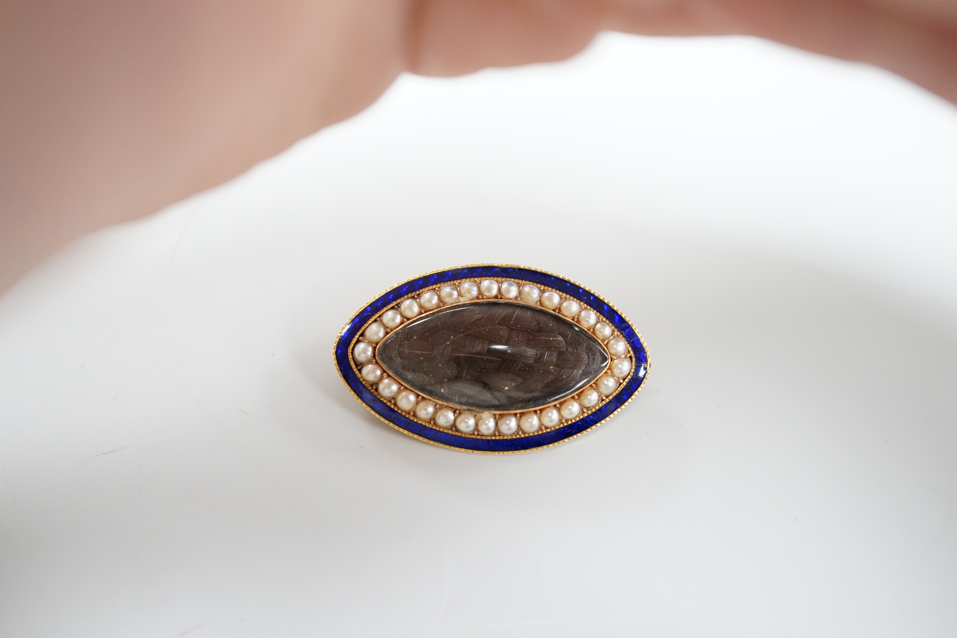 A Regency gold, enamel and split pearl brooch, of elliptical form with hairwork panel and monogram to the back, 3.75cm